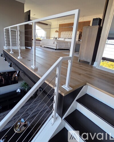 A modern staircase with white railings and black steps leads to a living room.