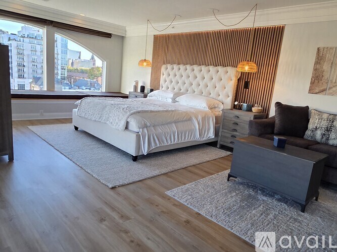A bedroom with a large bed, a nightstand, and a chair.