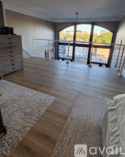 A room with wooden floors and a large window overlooking a cityscape.