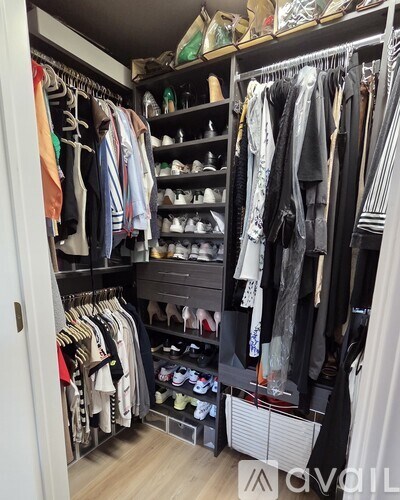 A black closet with clothes and shoes.