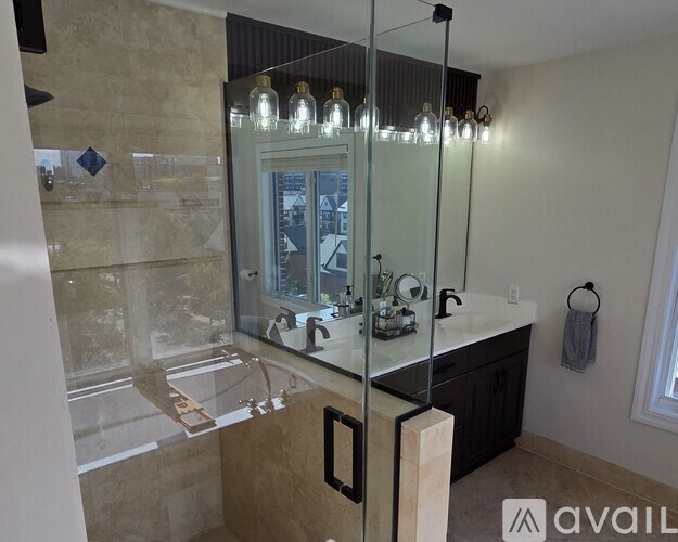 A bathroom with a glass shower door and a marble countertop.