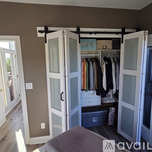 A room with a bed and a closet with glass doors.