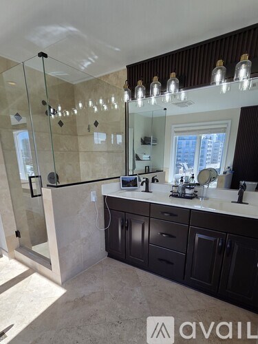 A bathroom with a glass shower enclosure and a vanity with a mirror above it.