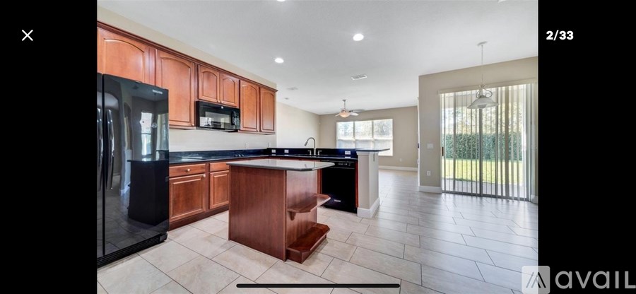 A kitchen with wooden cabinets and a black refrigerator.