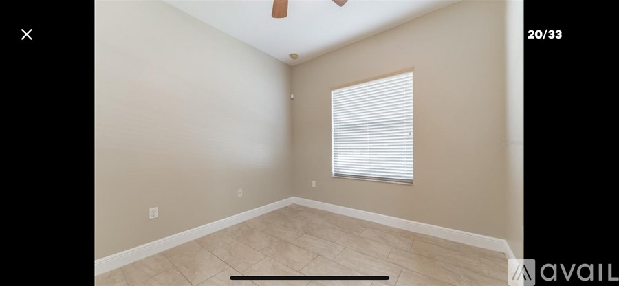 A room with beige walls and a window with blinds.