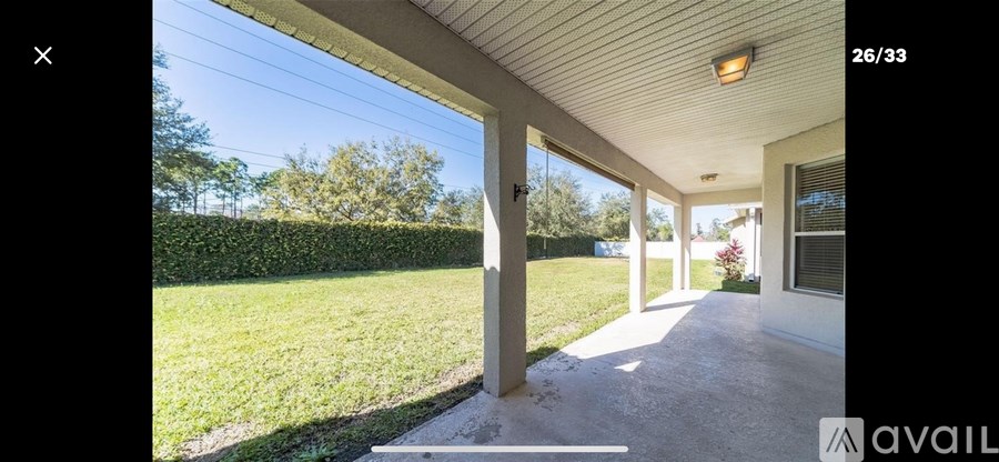 A house with a white porch and a hedge in the background.