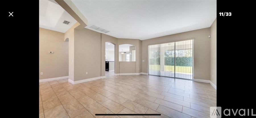 A spacious room with tiled flooring and a sliding glass door leading to a balcony.