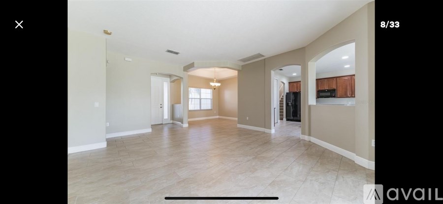 A spacious living room with a high ceiling and a large window.