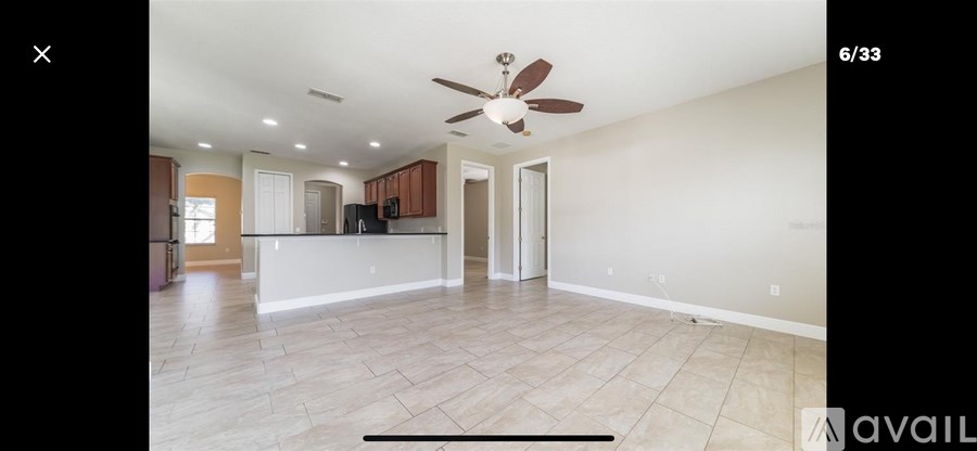 A spacious living room with a ceiling fan and tiled flooring.