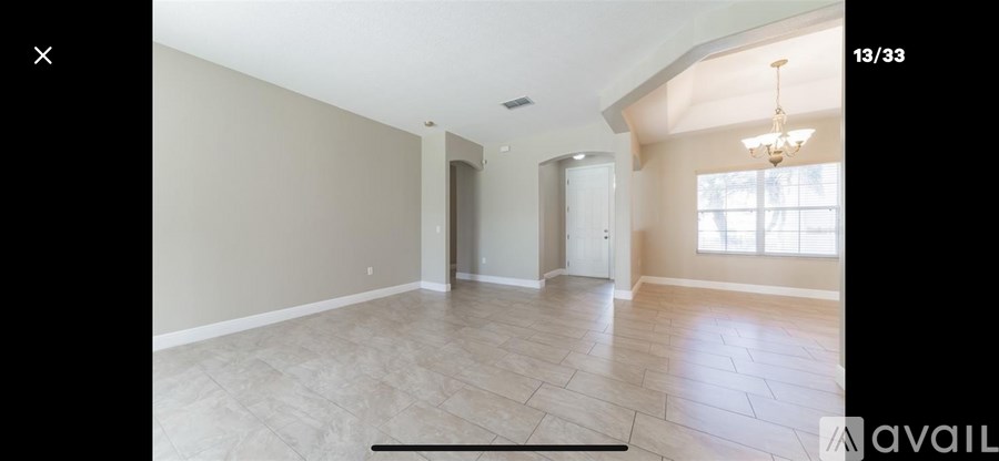 A spacious room with a chandelier and large windows.