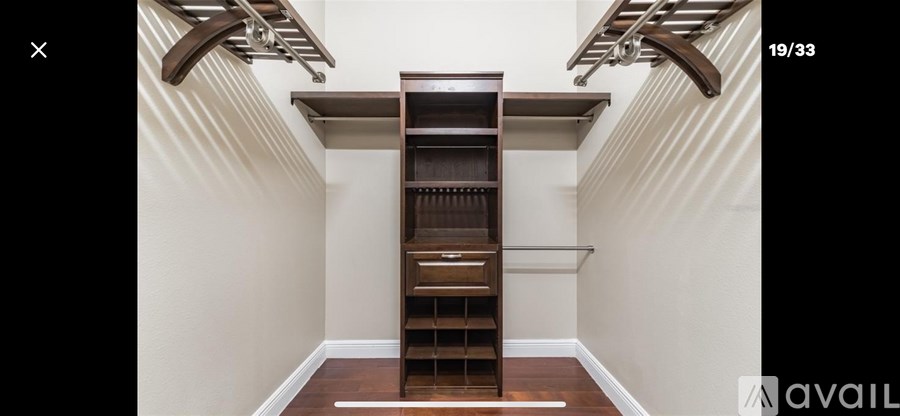 A white wall with a shelf and a wooden floor.