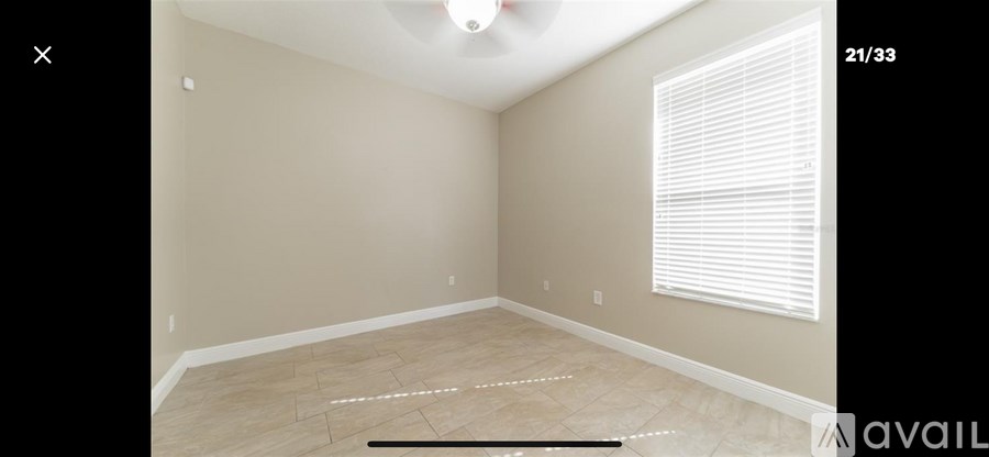 A room with beige walls and a window with blinds.