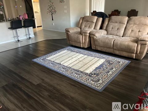 A living room with a row of recliner chairs and a rug in the middle.