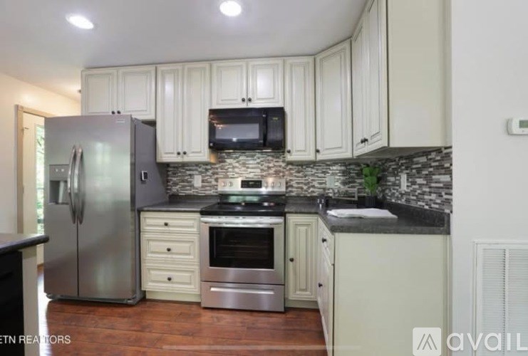A kitchen with a refrigerator, oven, microwave, and cabinets.