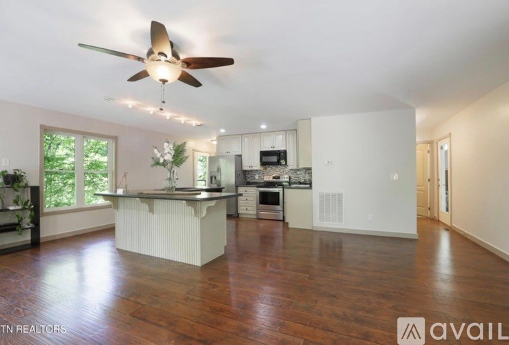 A spacious kitchen with a fan and wooden floors.