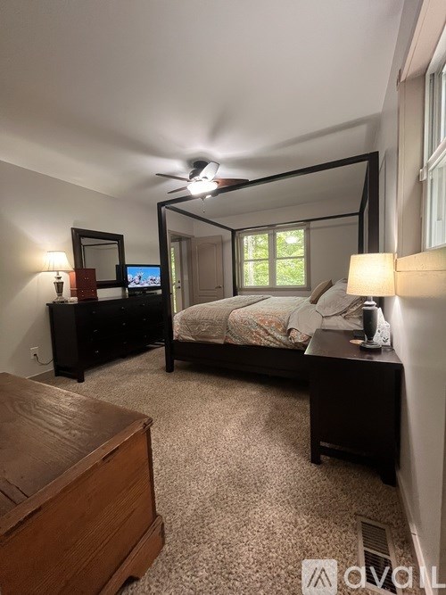 A bedroom with a bed, dresser, and ceiling fan.