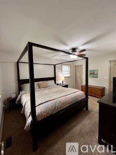 A bedroom with a four poster bed and a ceiling fan.