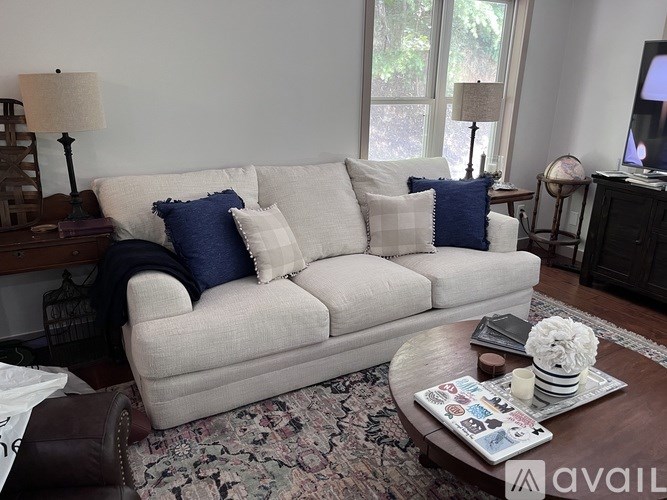 A white couch with blue pillows and a decorative tray on a coffee table.