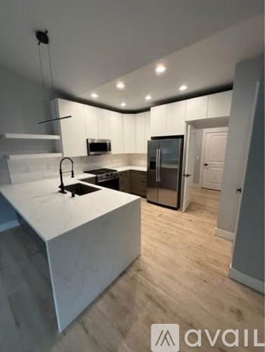 A modern kitchen with a white countertop and wooden flooring.