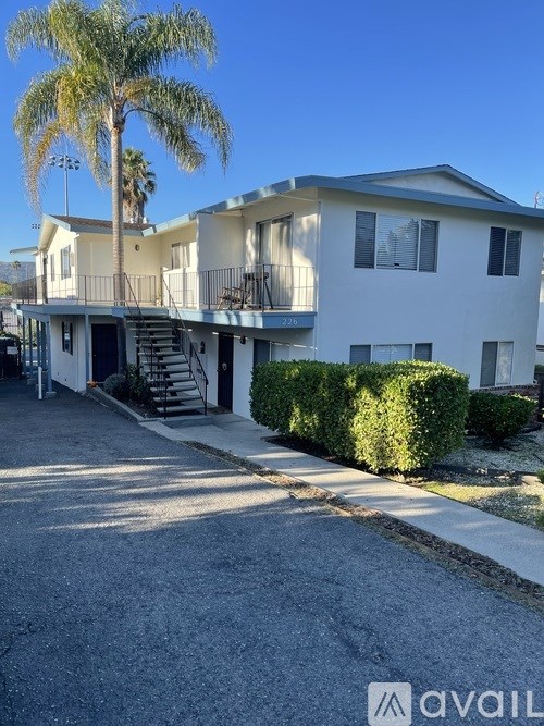A two-story house with a balcony and a palm tree in front.