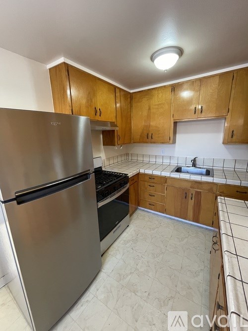 A kitchen with a stainless steel refrigerator and wooden cabinets.