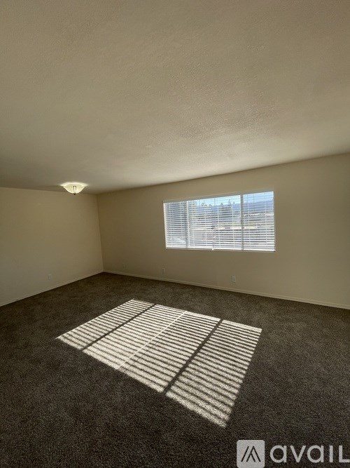 A room with a carpeted floor and a window with blinds.