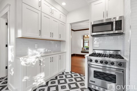 A kitchen with white cabinets and a black and white checkered floor.