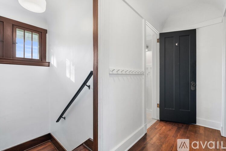 A hallway with a black door and a window with white walls.
