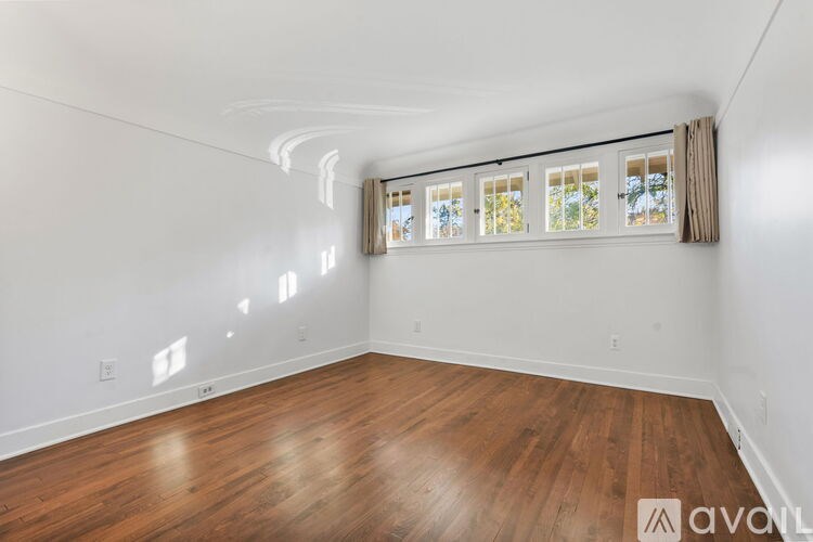 A room with wooden flooring and a window with blinds.