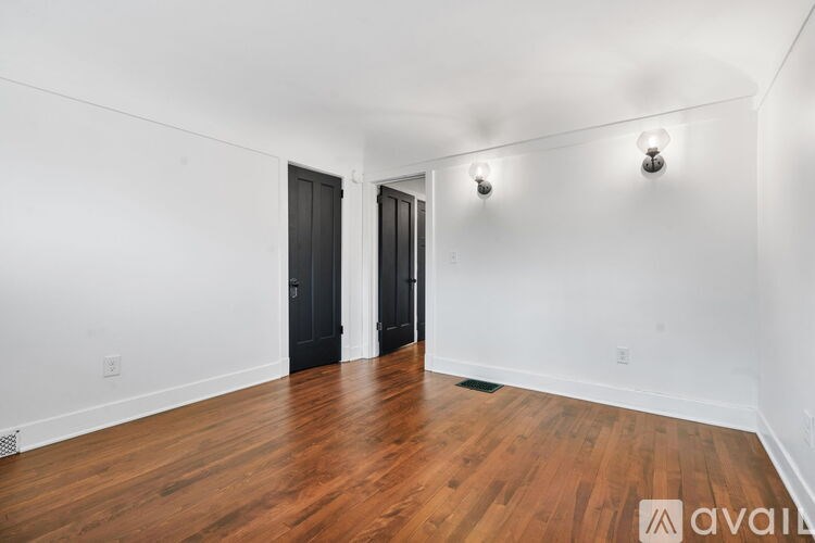 A room with wooden floors and two black doors.