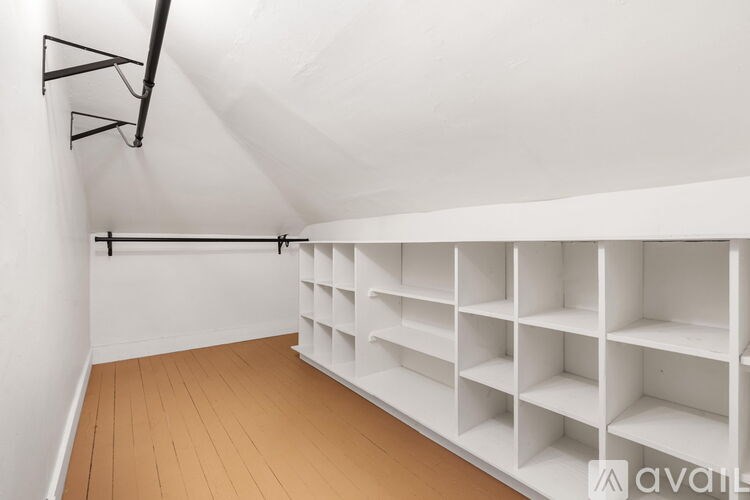 A room with white shelves and wooden flooring.