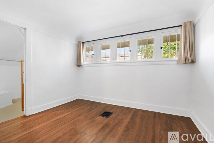 A room with wooden floors and a window with blinds.