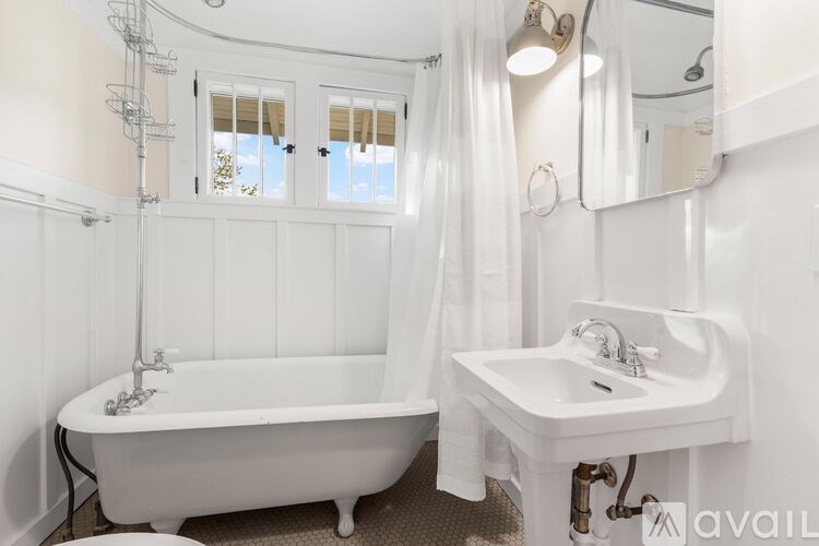 A white bathroom with a tub, sink, and mirror.