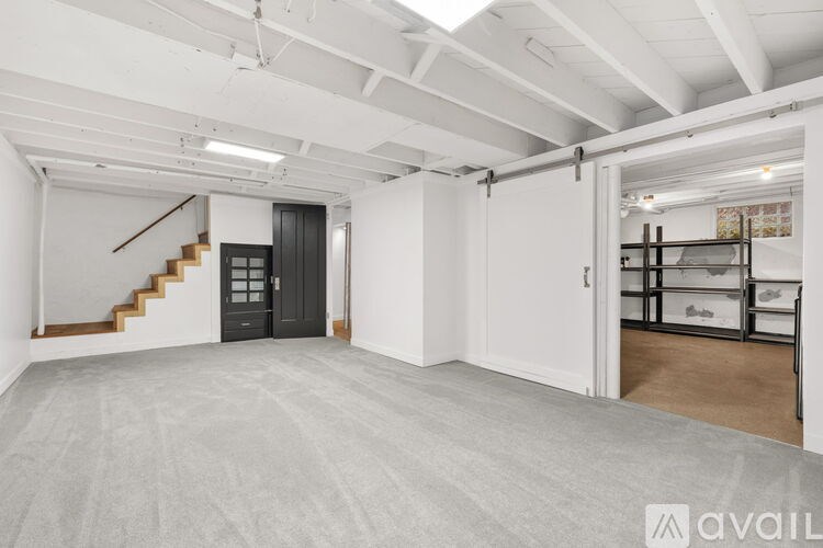 A spacious room with a staircase and a black door.