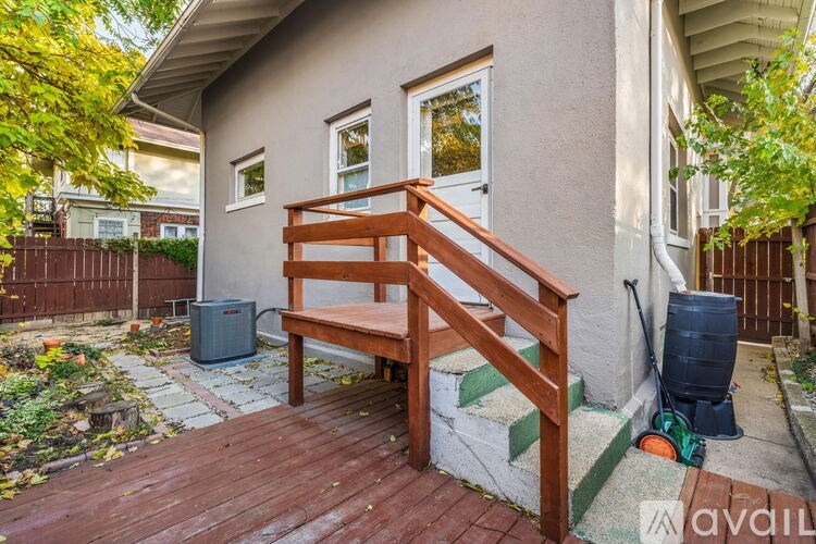 A wooden staircase with a bench leads to a door on a house.