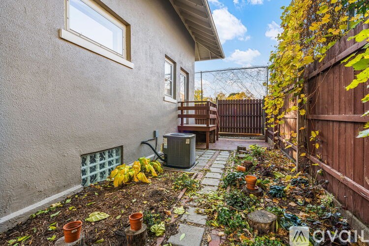 A small backyard with a patio and a wall with a window.