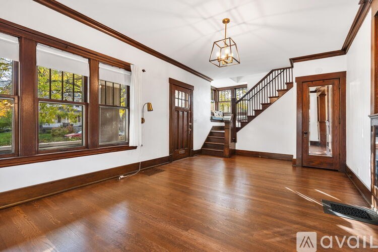 A spacious room with wooden floors and a staircase.