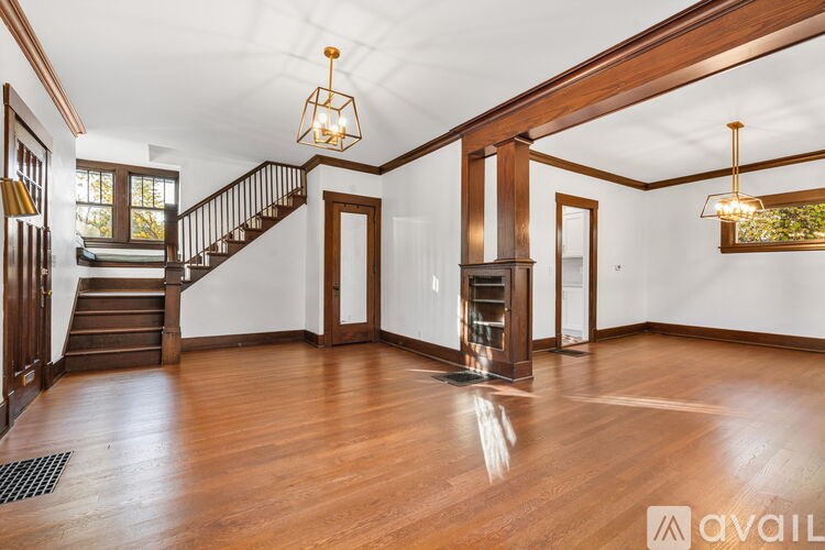 A spacious room with wooden floors and a staircase.