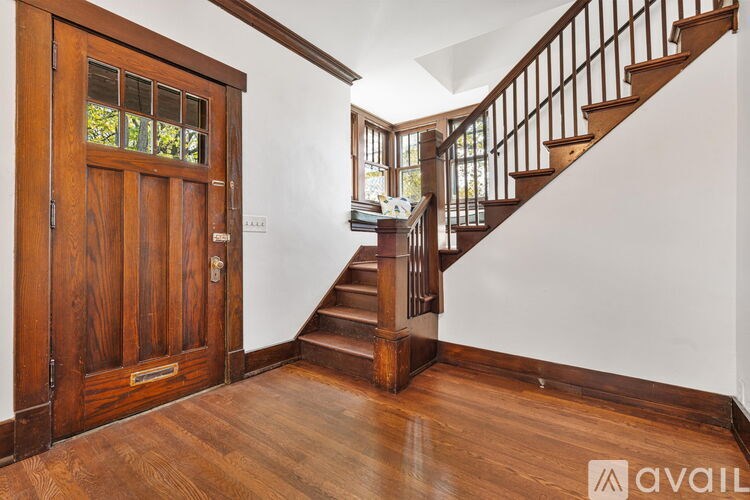 A wooden staircase with a white wall on the side and a wooden door with a glass window on the left.