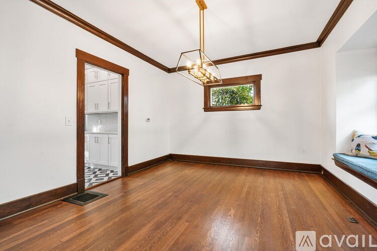 A room with wooden floors and a large window with a view of greenery.
