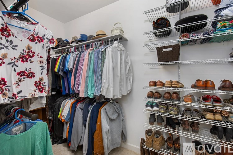 A room with a shoe rack and clothes hanging up.