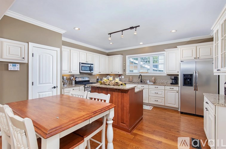 A kitchen with a wooden table and white chairs.