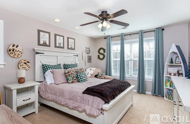 A bedroom with a bed, a ceiling fan, and a window with curtains.
