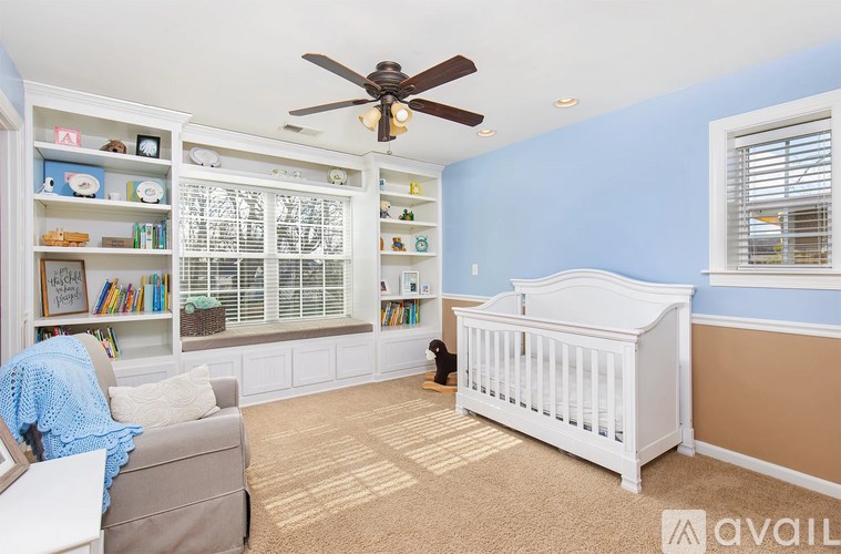 A baby's room with a white crib and a ceiling fan.
