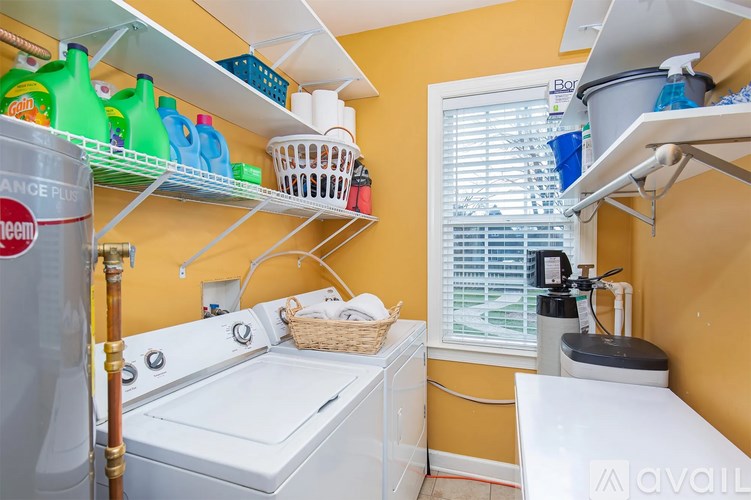 A laundry room with a washer and dryer, a window with blinds, and a shelf with cleaning supplies.