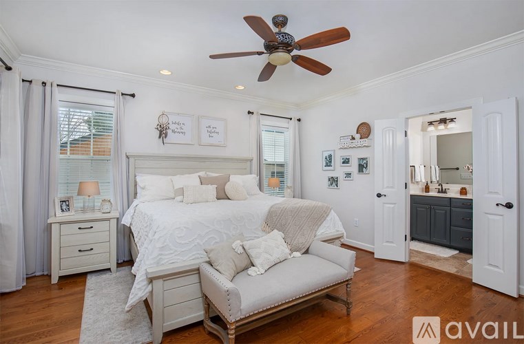 A bedroom with a bed, a couch, and a ceiling fan.