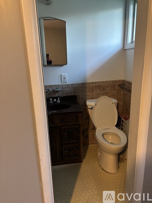 A white toilet is in a bathroom with a mirror above it.