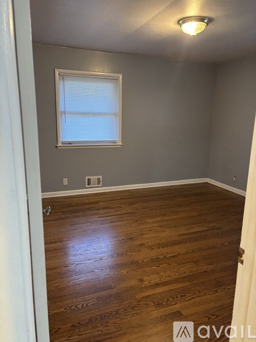 A room with wooden flooring and a window with blinds.