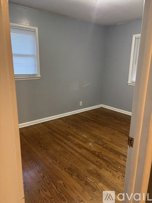 A room with wooden flooring and a window with blinds.