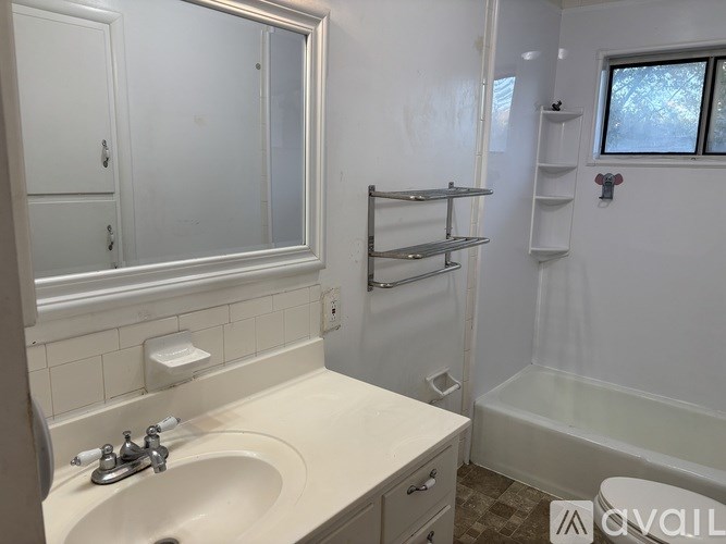 A white bathroom with a sink, mirror, and bathtub.